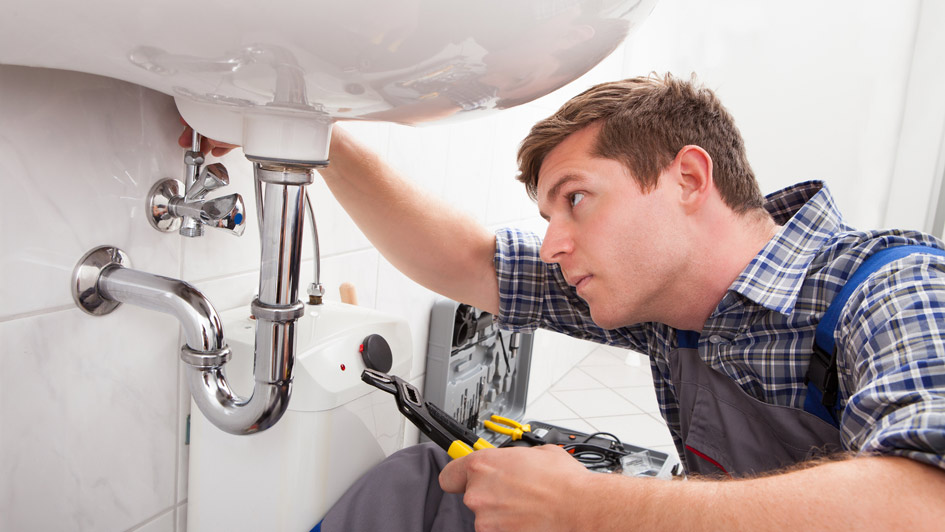 Professional plumber working in a kitchen